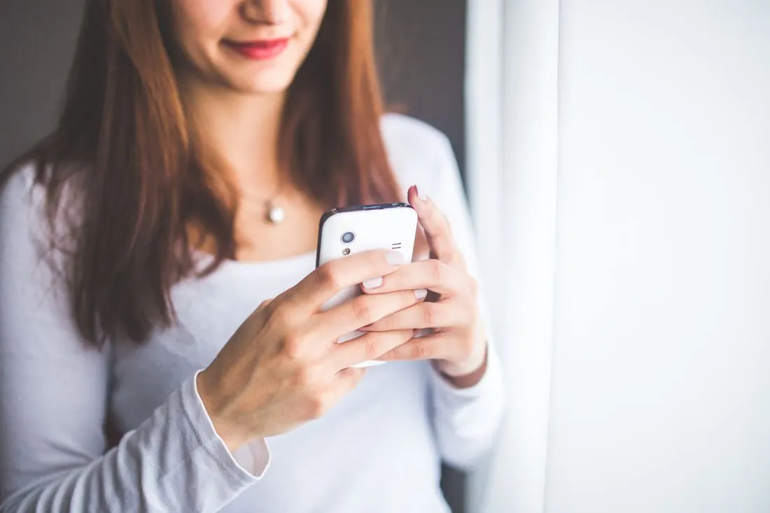 Une mère regarde son téléphone en souriant